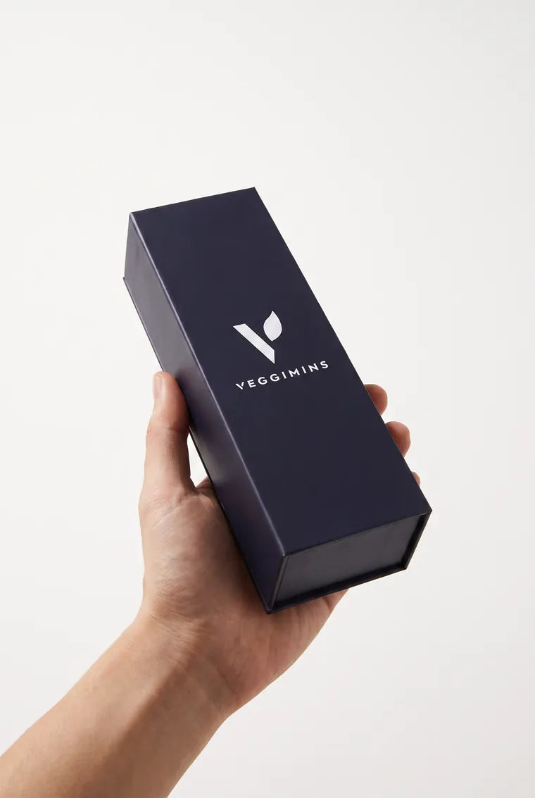 The closed navy Veggimins box held in one hand, showing its size